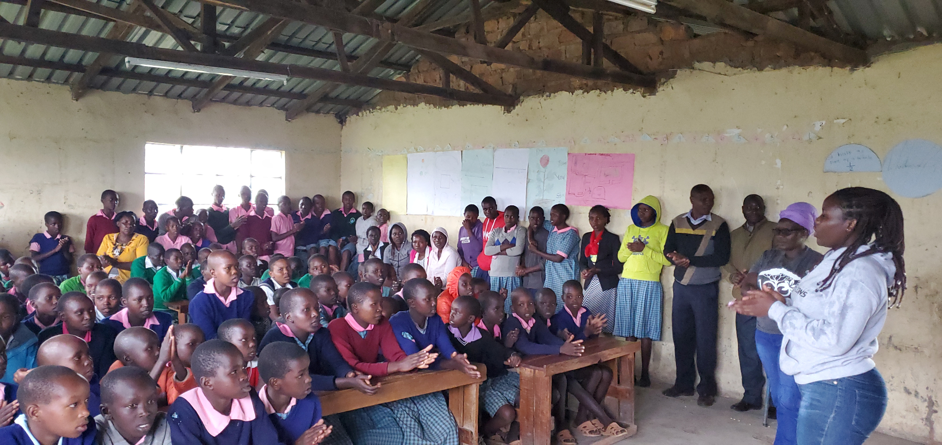 A full classroom of students in Kenya listening to a health education presentation during a HopeKit distribution