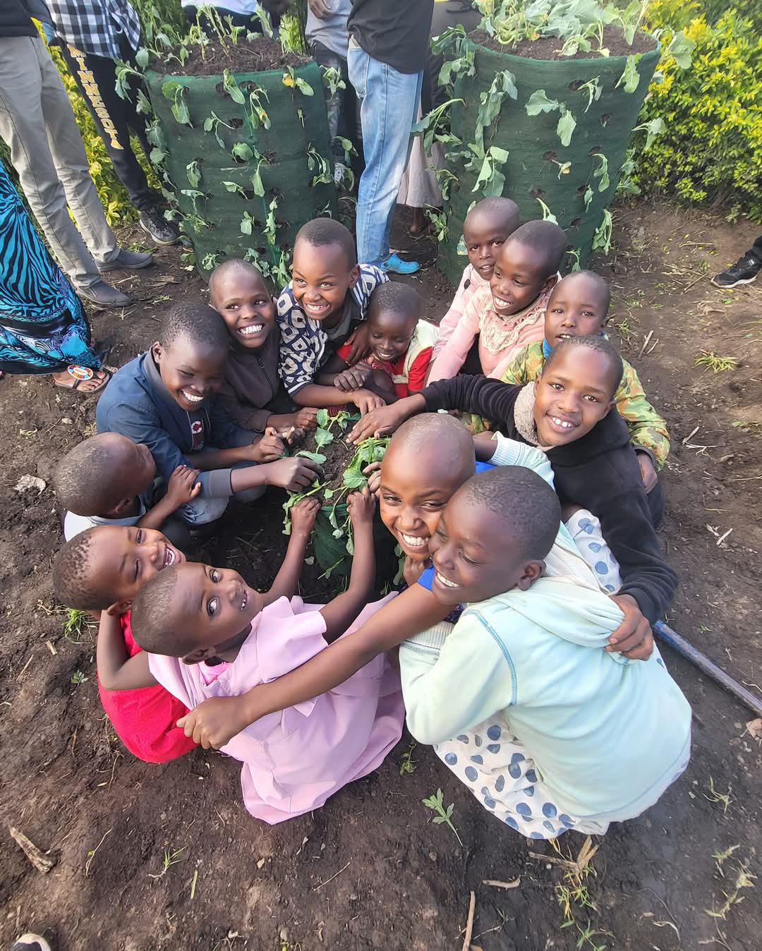 Kenyan children gathered around a Garden Tower, smiling up at the camera