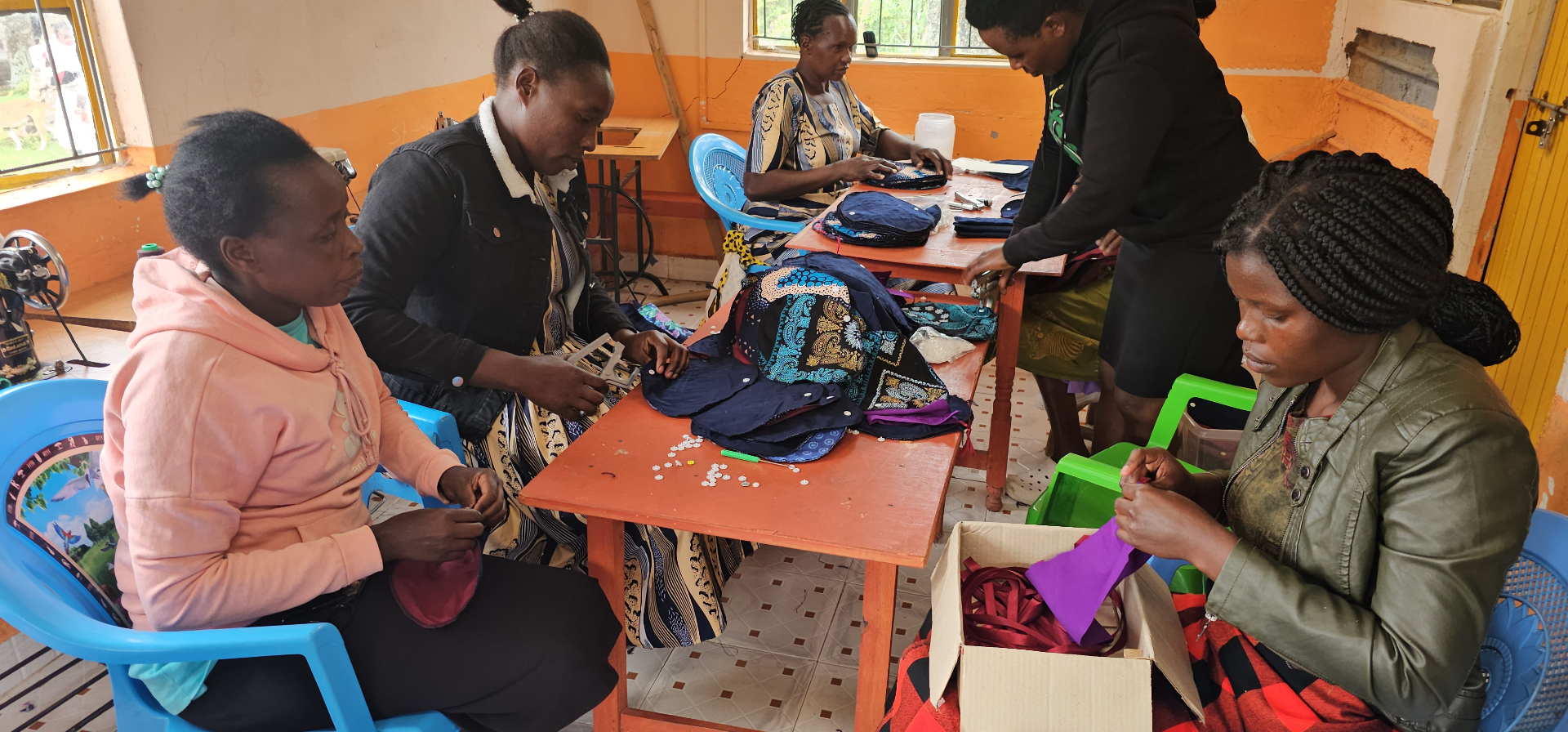 Kenyan seamstresses sewing reusable feminine hygiene kits at a HopeKit workshop, creating local employment