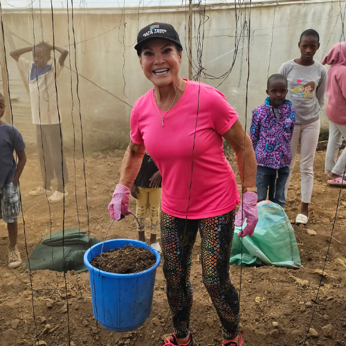 Mary Crafts carrying a bucket of soil while building garden towers in Kenya with local children