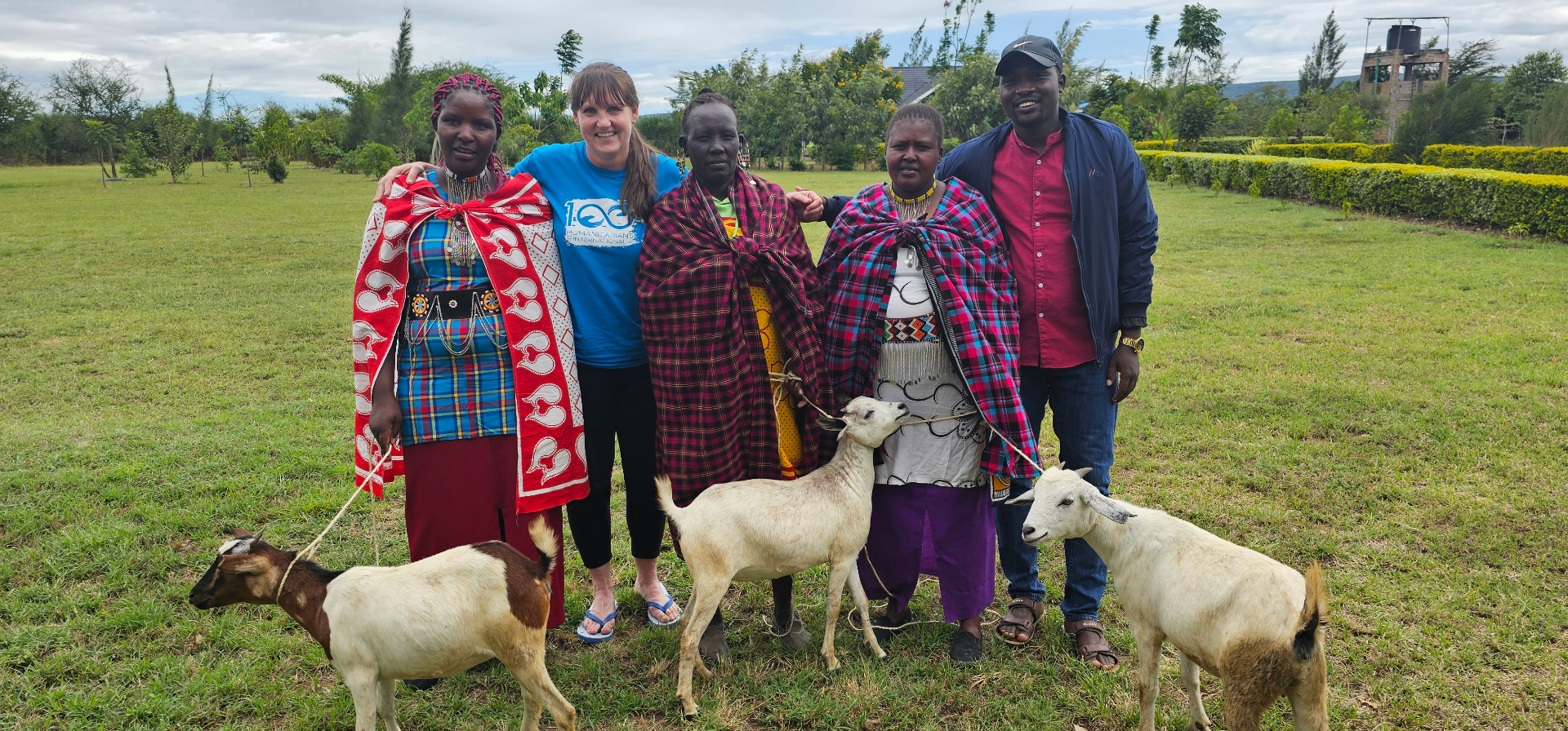 Maasai women and a community director standing with their goats in Kenya