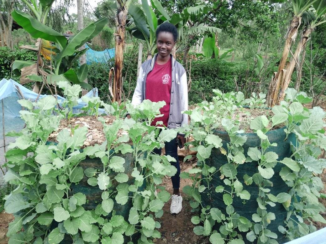 A young woman in Kenya standing proudly beside Garden Towers